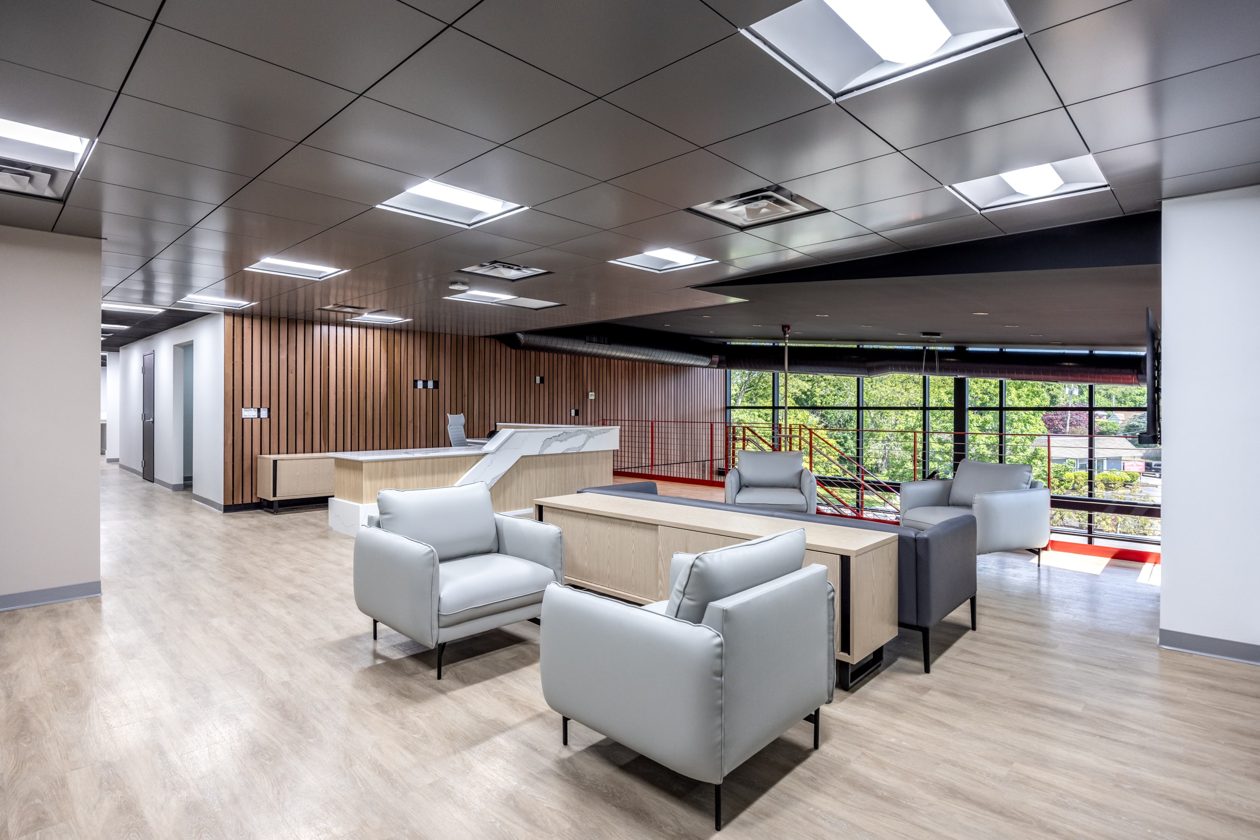 Open concept lobby on the second floor, featuring a front desk in the background with a few chairs arranged for casual seating and conversation.